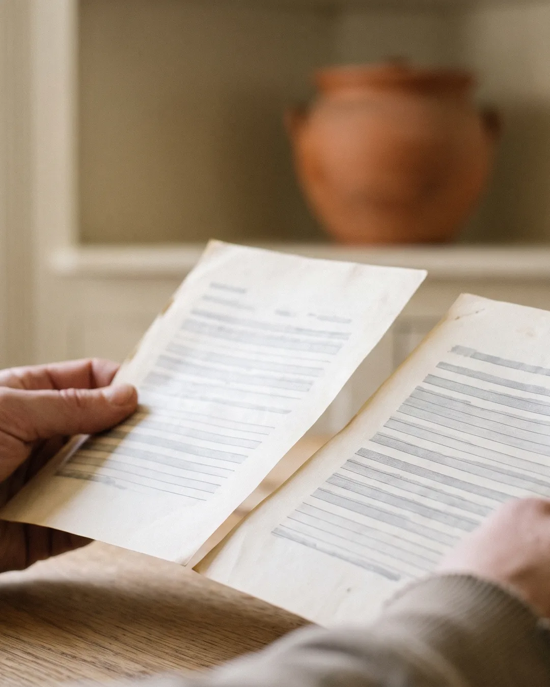 Two hands hold up two printed statements side by side to compare them.